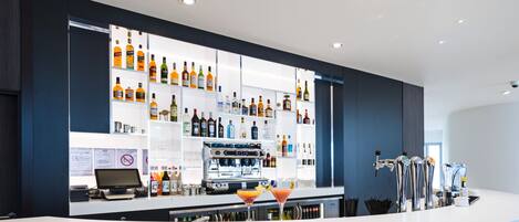 A modern bar area with a variety of liquor bottles, a coffee machine, and a martini glass.