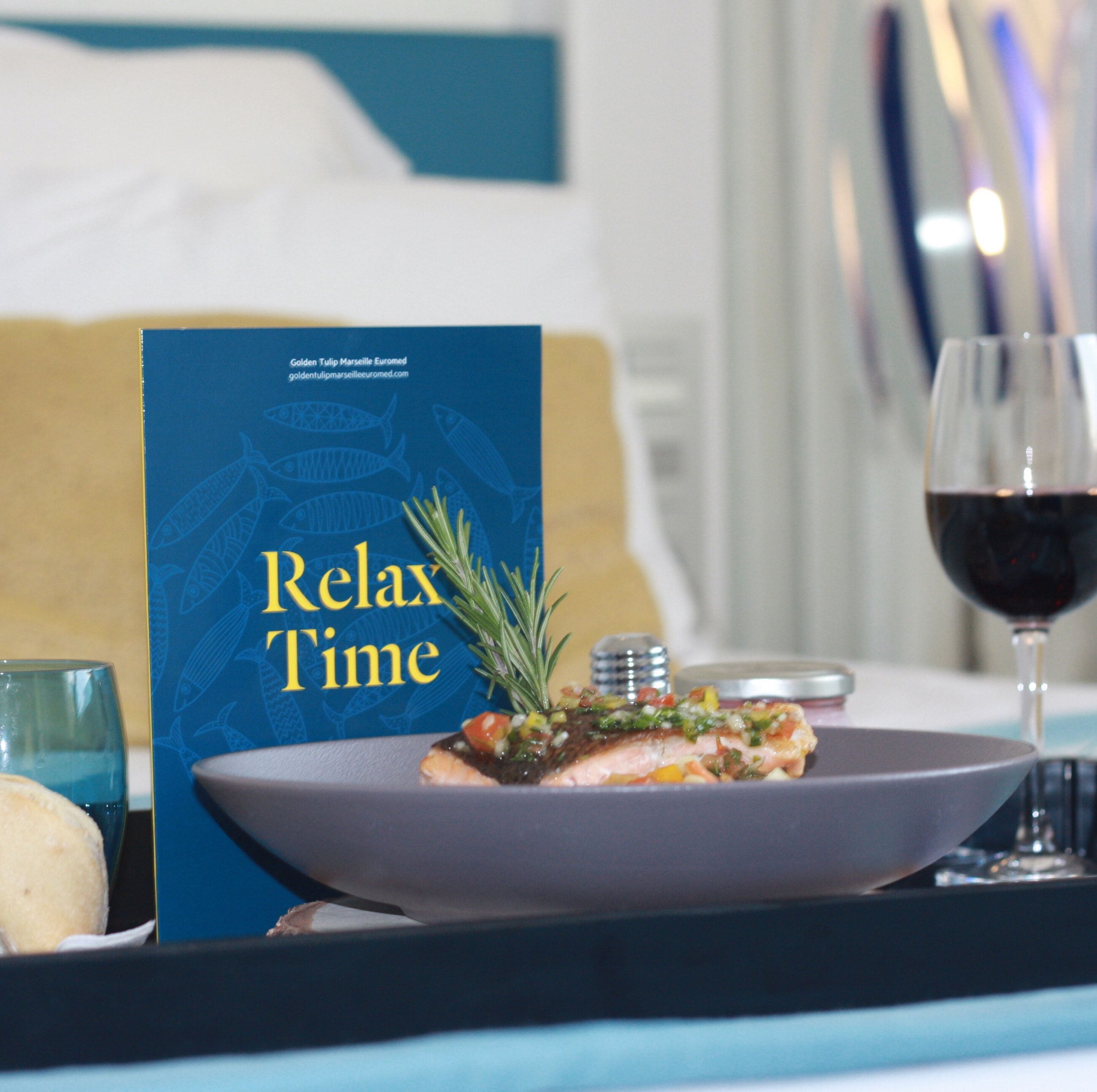 Una mesa de comedor con un plato de comida, una copa de vino tinto y un menú que dice 'Relax Time'.