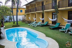 Una piscina al aire libre, sillones reclinables de piscina