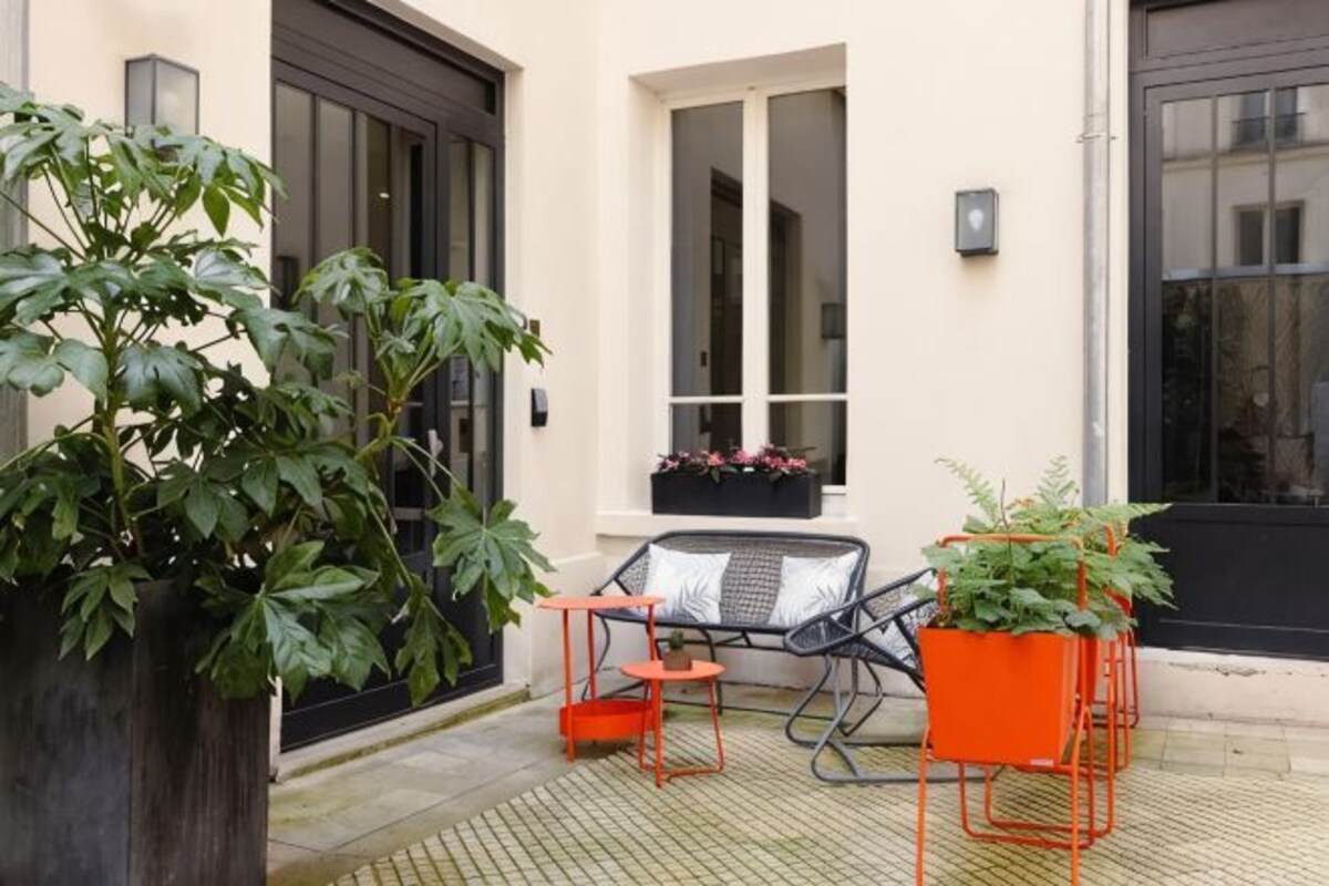 A patio with a large planter, two chairs, and a small table.