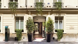 A building facade with large potted plants, a visible entrance, and a number '34' sign. - Mayflower Opéra  (Paris)