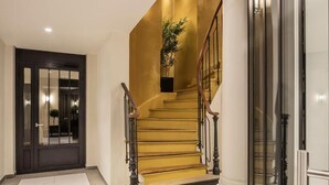 A staircase with a golden finish, a dark door, and a plant on the landing. - Mayflower Opéra  (Paris)