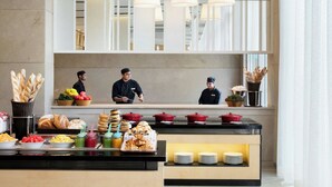 Een buffetgedeelte met diverse gerechten en een balie waar personeel aanwezig is.