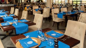 A restaurant with tables set for dining, featuring blue tablecloths and gold plates.