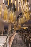 A modern interior with a central staircase, metallic railings, and hanging light fixtures.