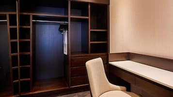 A walk-in closet with wooden shelving, a chair, and a mirror.