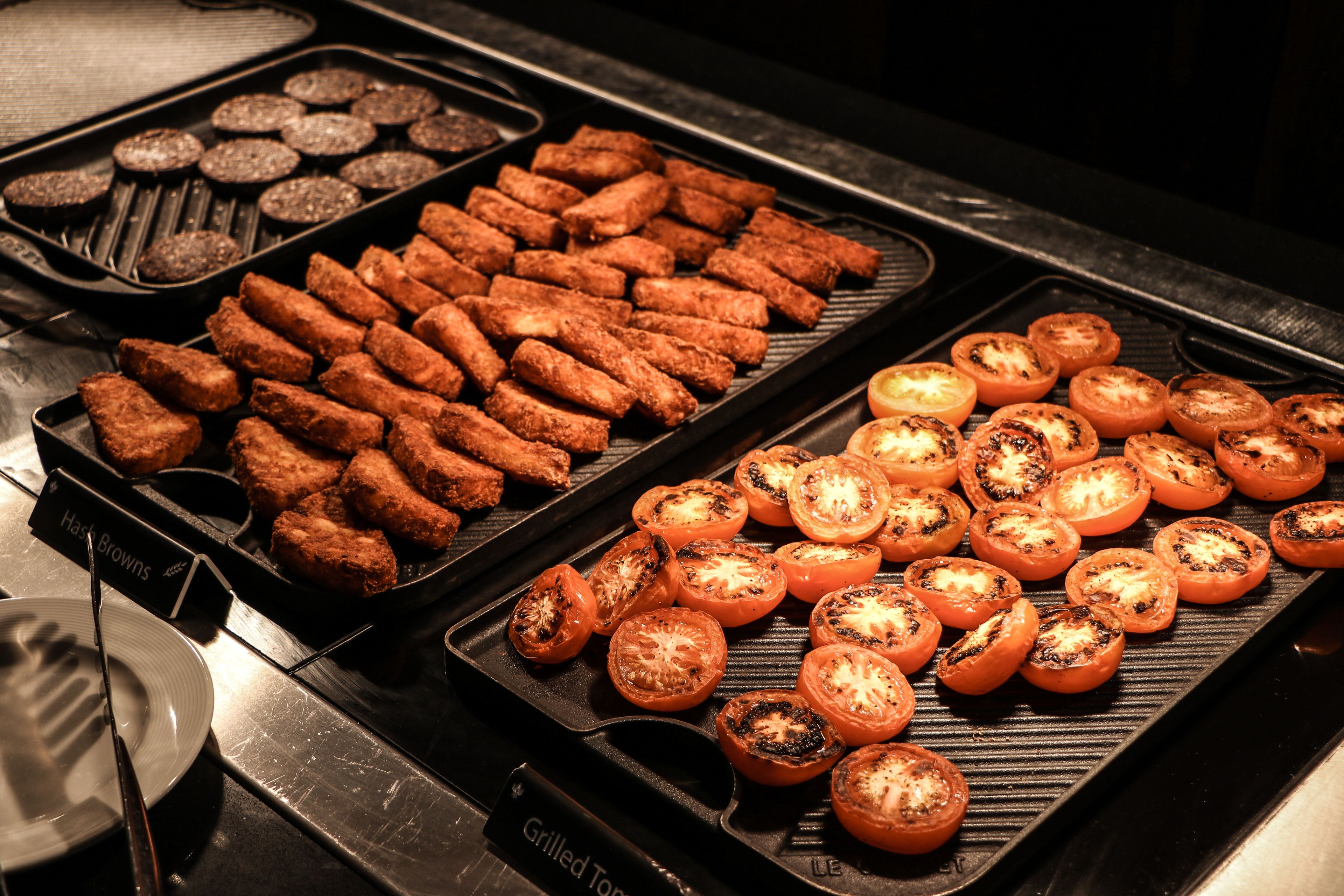 A grill with various foods, including grilled tomatoes and meat.