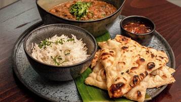 A plate with rice, naan bread, and a bowl of curry on a wooden table.