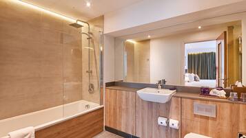 A modern bathroom with a glass-enclosed shower, a wooden vanity, a large mirror, and a visible toilet.