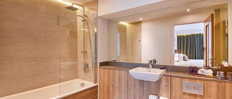 A modern bathroom with a glass-enclosed shower, a wooden vanity, a large mirror, and a visible toilet.