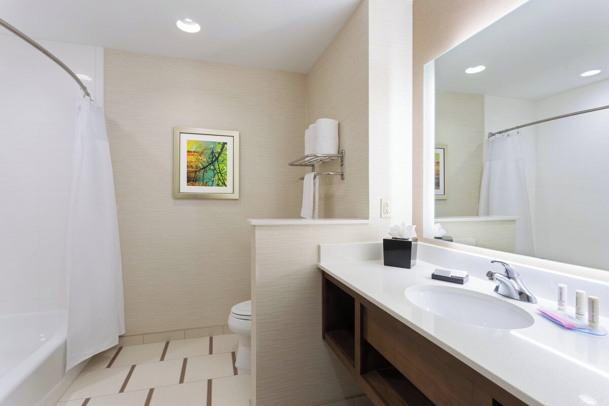 A modern bathroom with a bathtub, toilet, sink, and a large mirror.