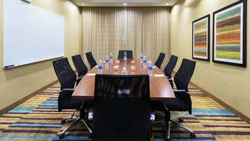 A conference room with a long table, black chairs, water bottles, and a whiteboard.