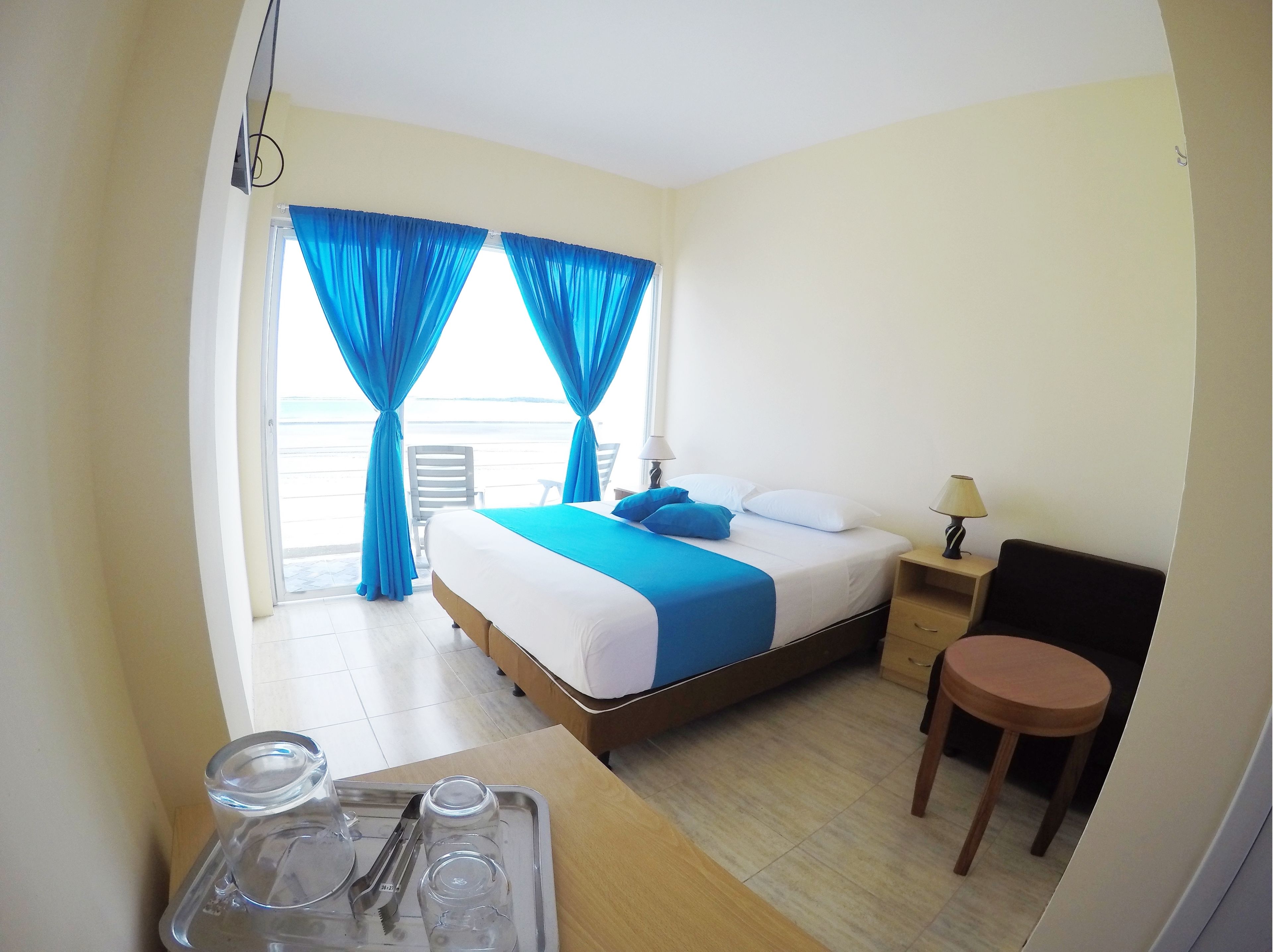 Una habitación de hotel con cama, mesita de noche, una silla y una mesa con bandeja.
