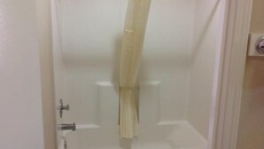 Et badeværelse med badeforhæng, toilet og vask.