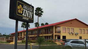 Et skilt med teksten DELUXE INN foran en gul bygning med rødt tag, markeret som en LUGTPLADS.