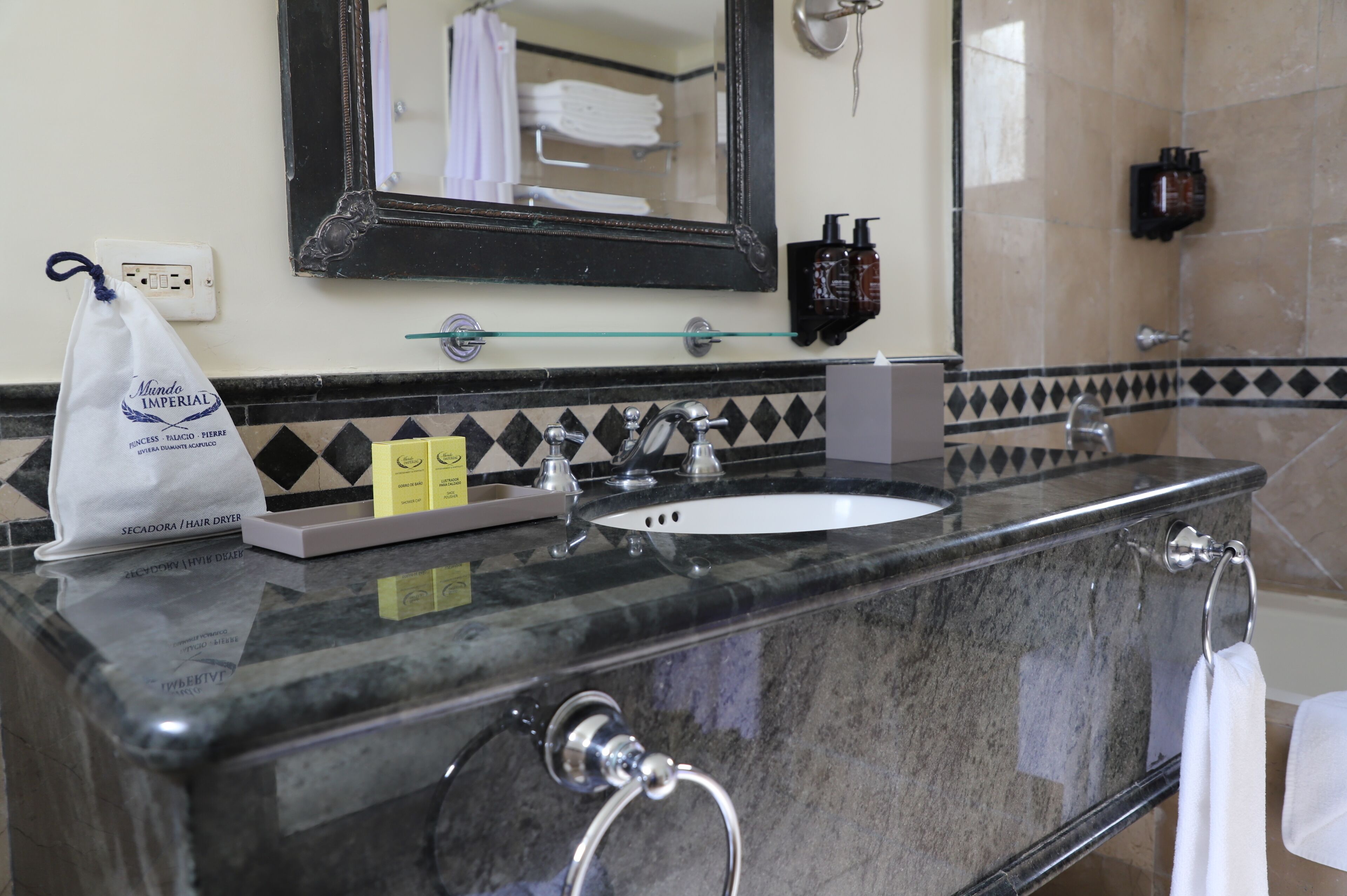 A bathroom with a marble sink, a mirror, a towel rack, and a bag of toiletries.
