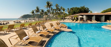 Relax by the oceanfront pool surrounded by lounge chairs and umbrellas.