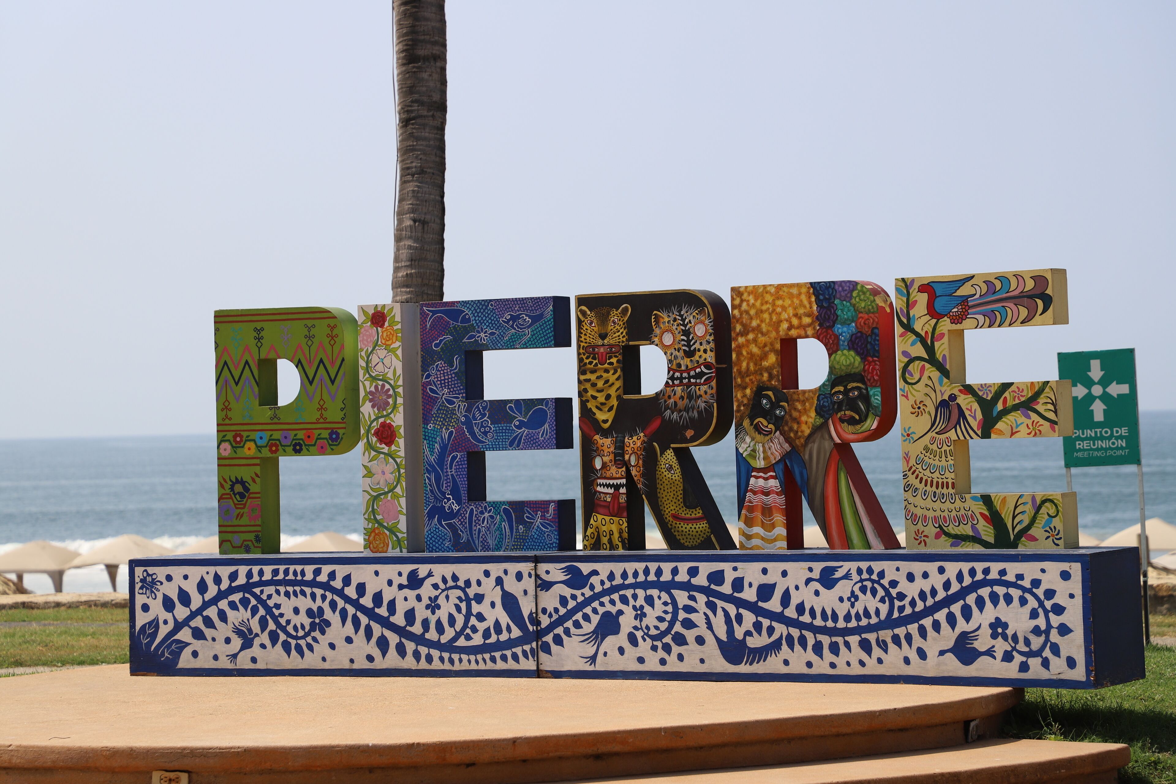 A colorful sign with the name 'PERRE' in large letters, set against a beach backdrop.