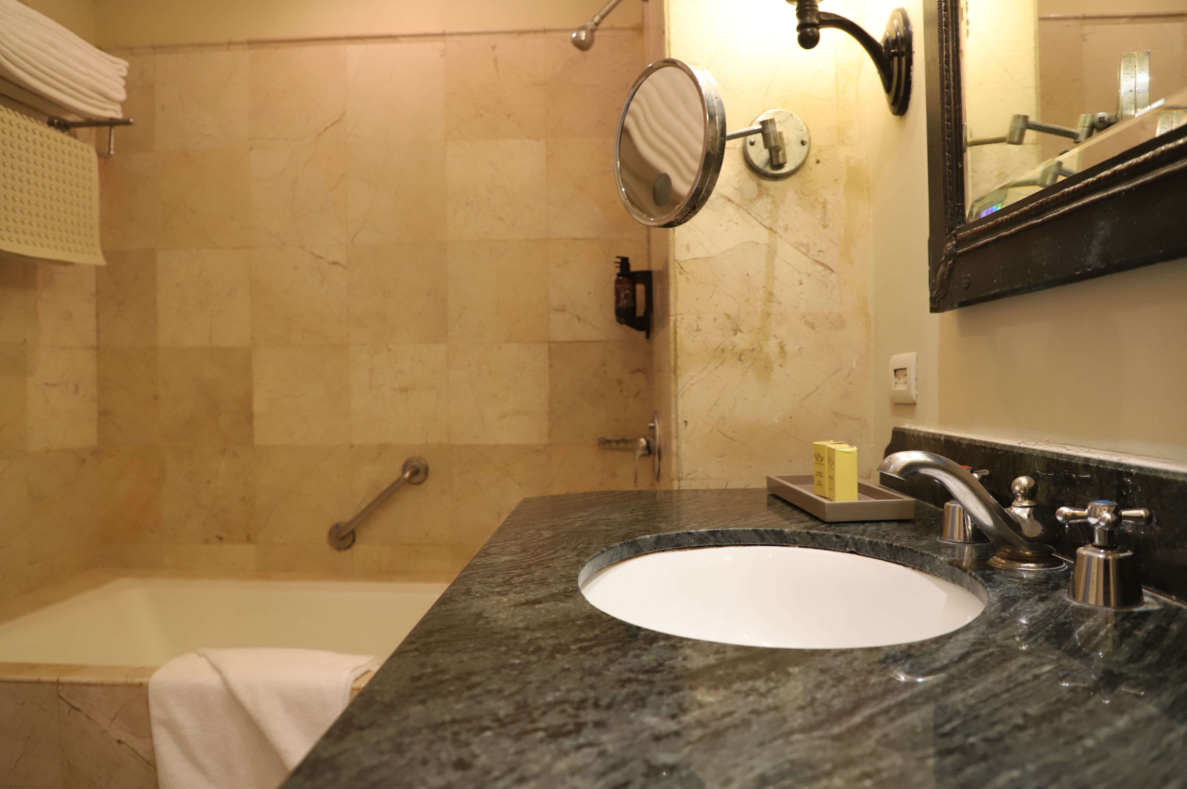 Un baño con bañera, lavabo, espejo y toallero.