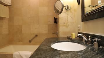 Un baño con bañera, lavabo, espejo y toallero.