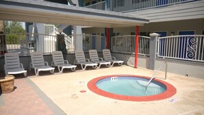 An outdoor swimming pool with lounge chairs and a red safety sign indicating a depth of 3 feet. - Texas Inn Alamo (Alamo)