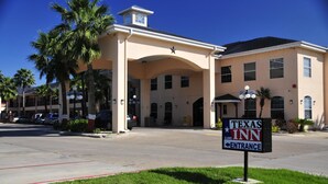 A Texas Inn building with a large entrance, palm trees, and a clear blue sky. - Texas Inn Alamo (Alamo)