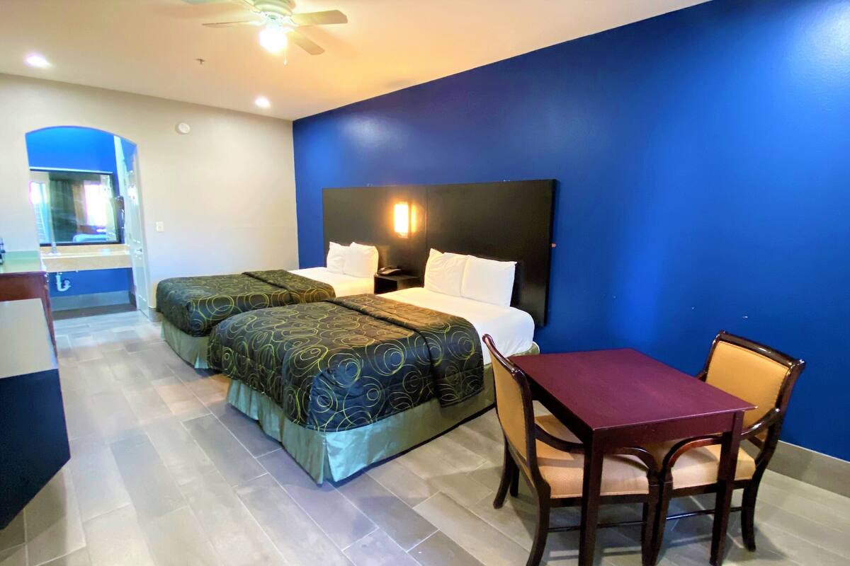 A hotel room with two beds, a desk, and a chair.