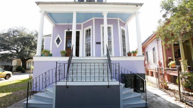 A two-story house with a front porch and a staircase leading to the entrance. - Esplanade Suites (New Orleans)