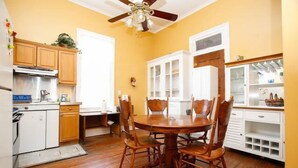 A kitchen with wooden cabinets, a dining table with chairs, and a ceiling fan. - Esplanade Suites (New Orleans)