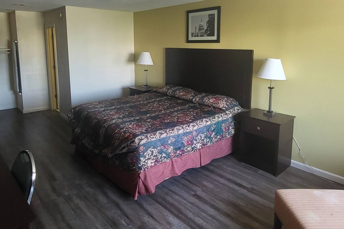 A hotel room with a bed, two bedside tables with lamps, a chair, and a small table.