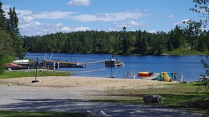 Zona junto al lago con un muelle, barcos y un área de picnic.