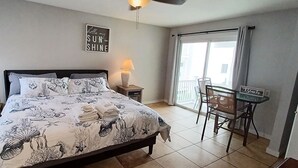 A bedroom with a bed, a nightstand, a desk, and a chair. - Breakers by the Sea (Hampton)
