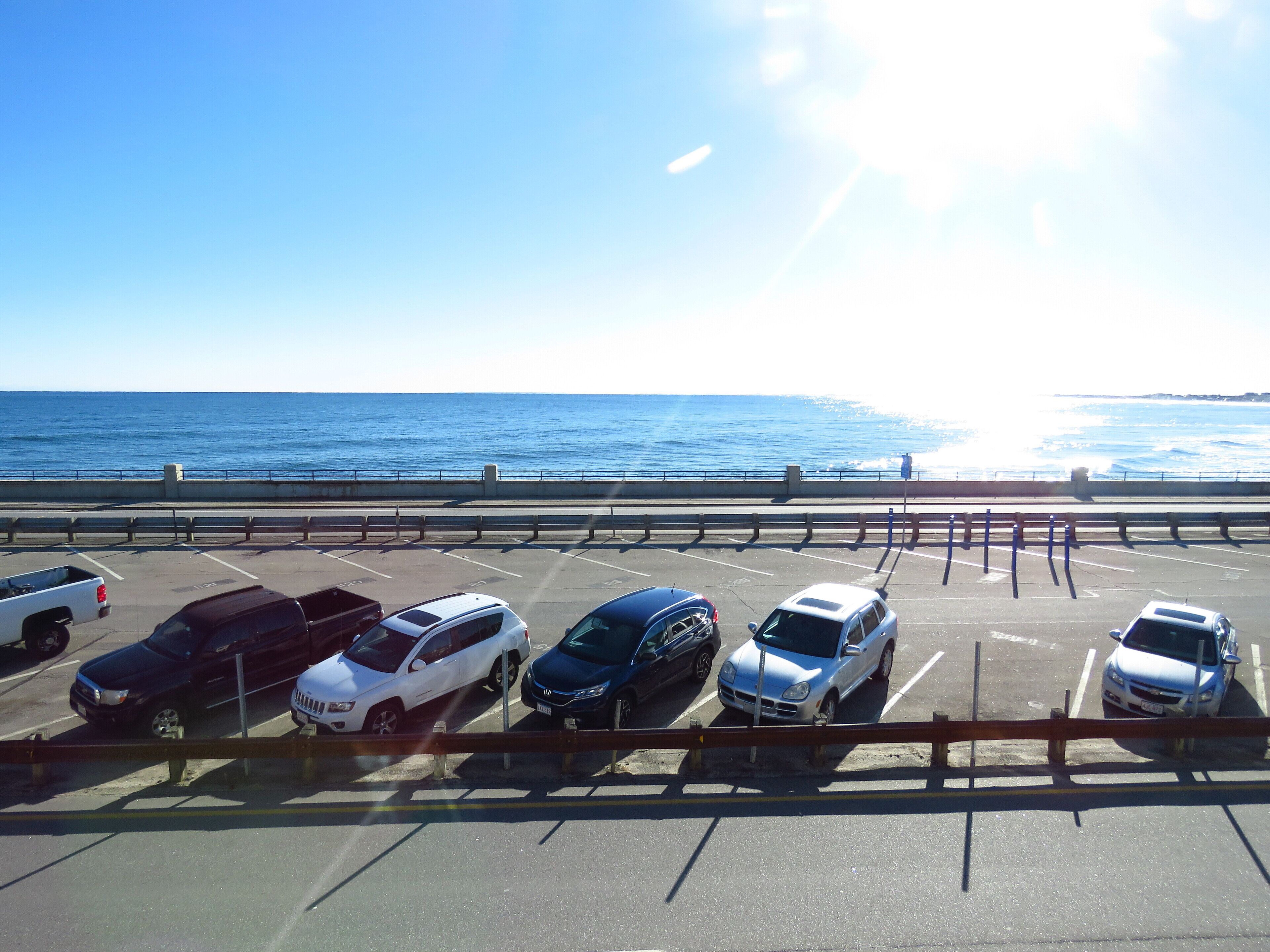 Un parking avec des voitures garées devant une vue sur la côte.