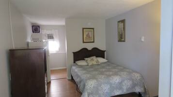A bedroom with a bed, a dresser, a window with curtains, and a ceiling fan.