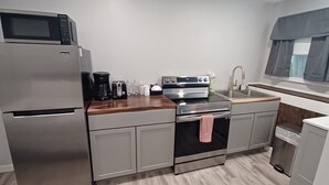 A compact kitchen with a refrigerator, microwave, coffee maker, toaster, and oven. - Breakers by the Sea (Hampton)