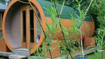 Cozy cabin nestled among lush greenery, featuring a charming door and windows.