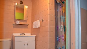 A bathroom with a white sink, a mirror, a towel rack, and a shower curtain with a flip-flop pattern. - Admiral Motel (Indianapolis)