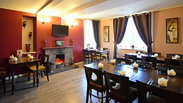 A dining area with tables set for guests, a fireplace, and artwork on the walls.