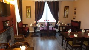A dining area with wooden tables and chairs, a fireplace, and artwork on the walls.