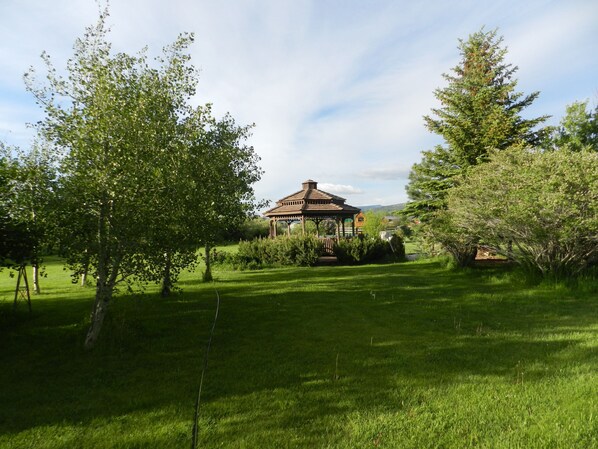 A gazebo in a grassy area with trees.