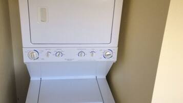A compact, white, front-loading washer and dryer unit with multiple control knobs and a small control panel.