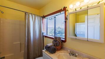Un baño con bañera, lavamanos y ventana con persianas.