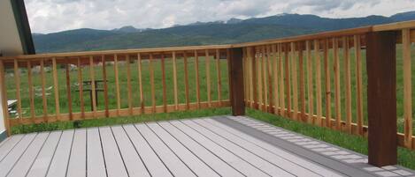 A wooden deck with a view of green fields and mountains.