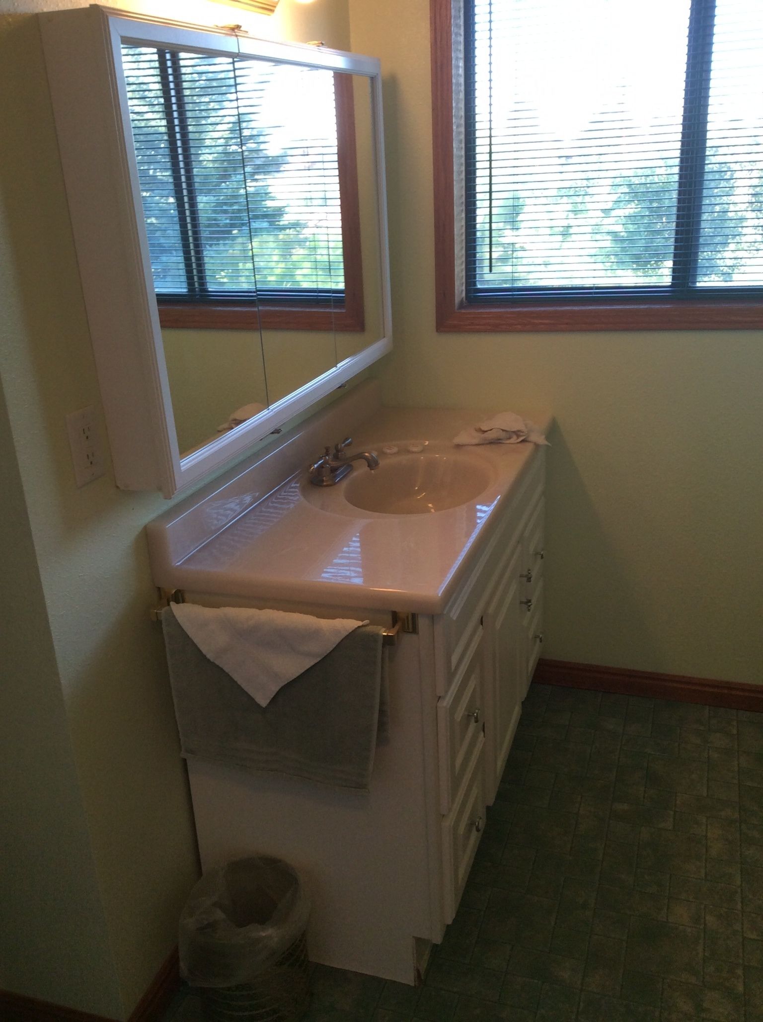 A small bathroom with a sink, mirror, and window.
