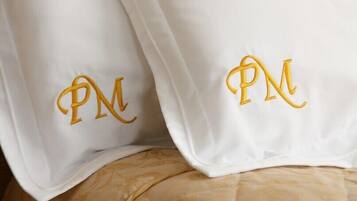 Two white pillows with embroidered initials "PM" in gold.