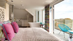 A bedroom with a large bed, a bathroom, and a balcony with a chair and table. - Park Manor Hotel (Scarborough)