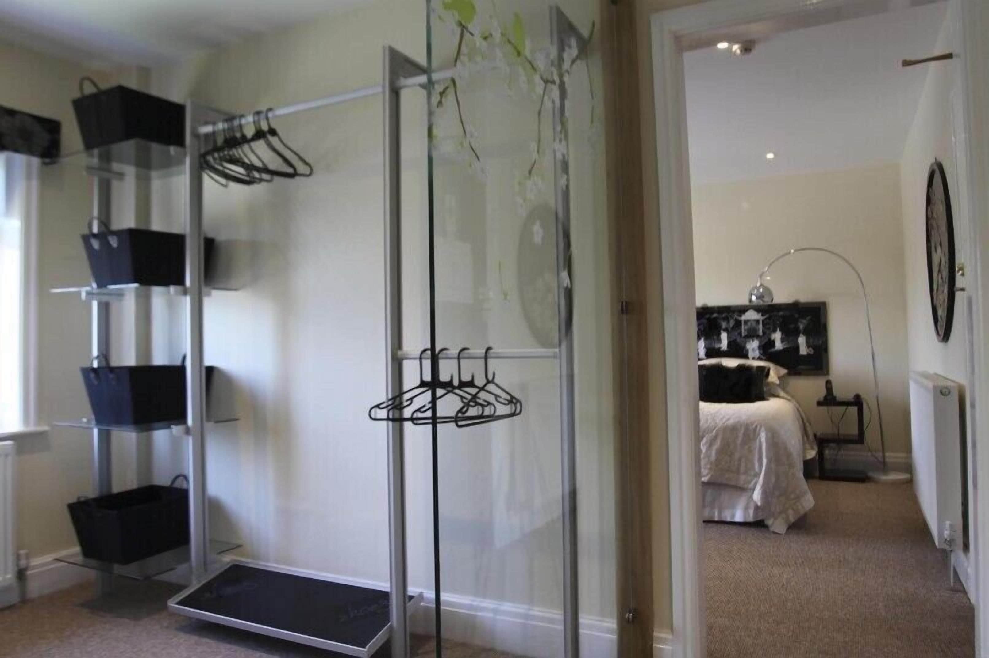 A room with a glass partition, a bed with a white duvet, a black and white artwork on the wall, and a radiator.