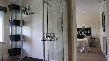 A room with a glass partition, a bed with a white duvet, a black and white artwork on the wall, and a radiator.