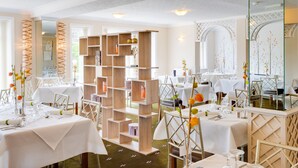 A dining area with white tables, wooden shelves, and decorative vases. - Park Manor Hotel (Scarborough)