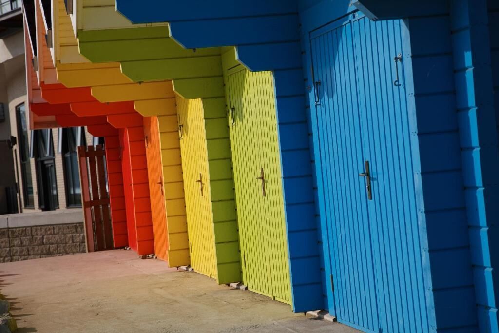 A row of colorful doors, each with a different color, leading to a building.